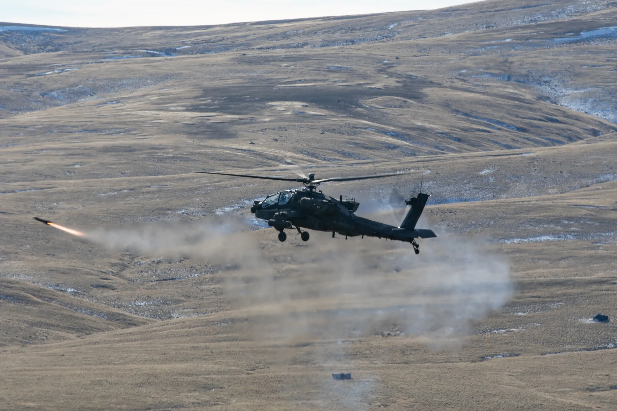 Apache hovering with Hellfire mid-flight on left side