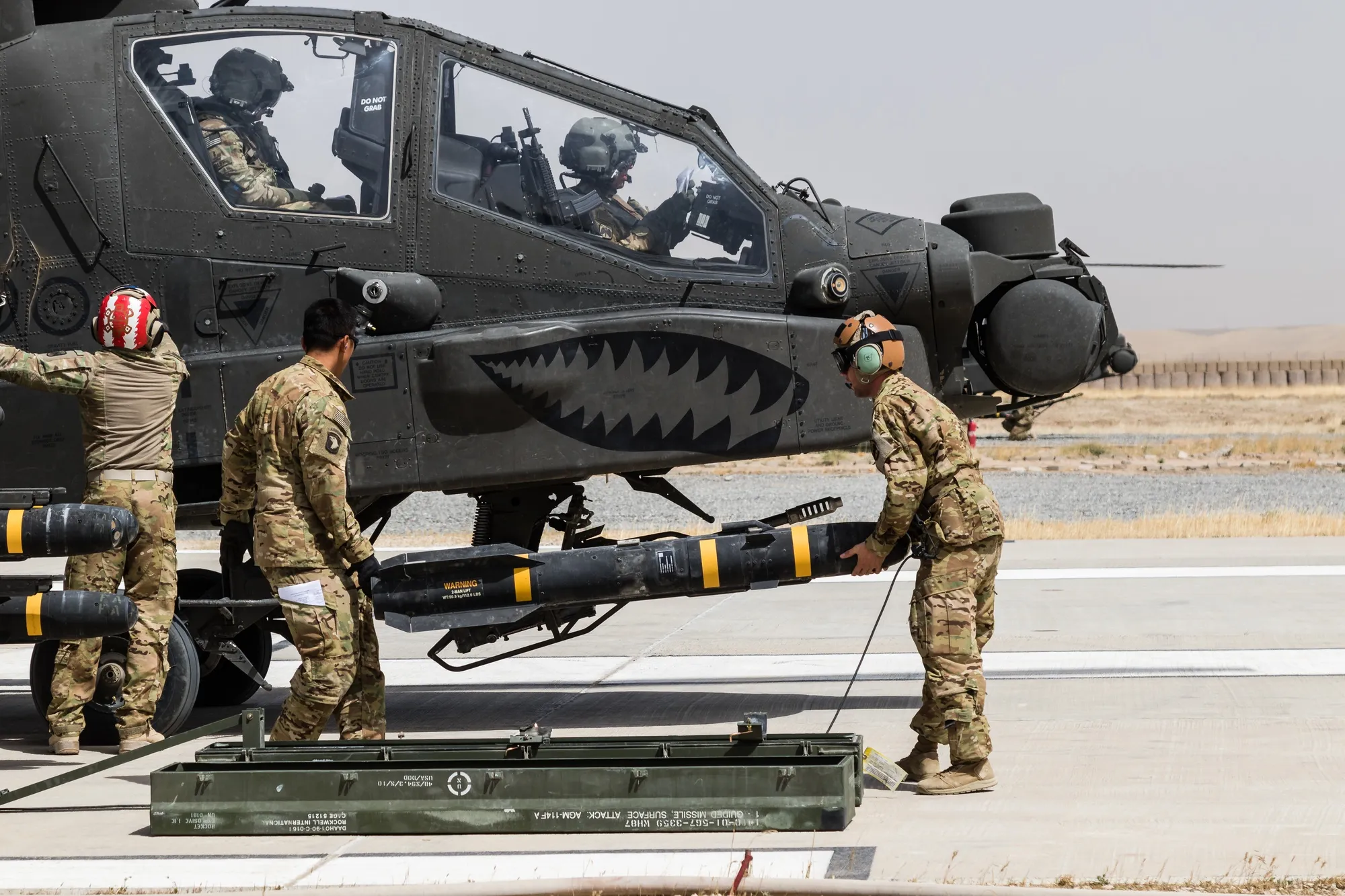 Ground crew loading AGM-114 Hellfire onto AH-64 Apache (shark-mouth nose art), Afghanistan