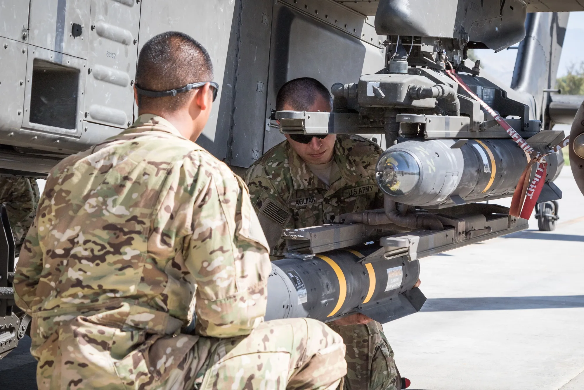 Soldiers mounting Hellfire missiles on Apache wing pylon