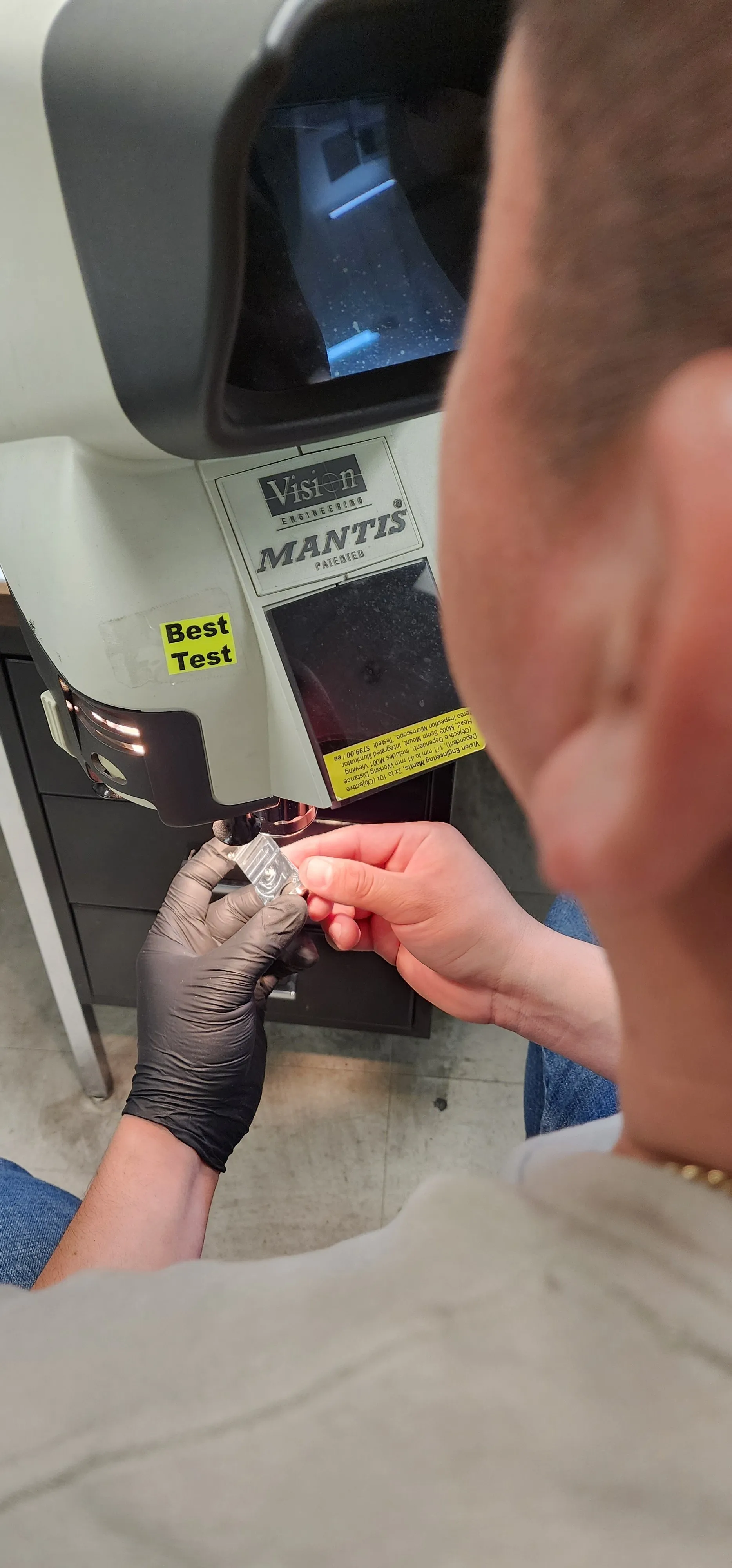 Technician inspecting a machined part under a Vision Engineering Mantis stereo-zoom microscope